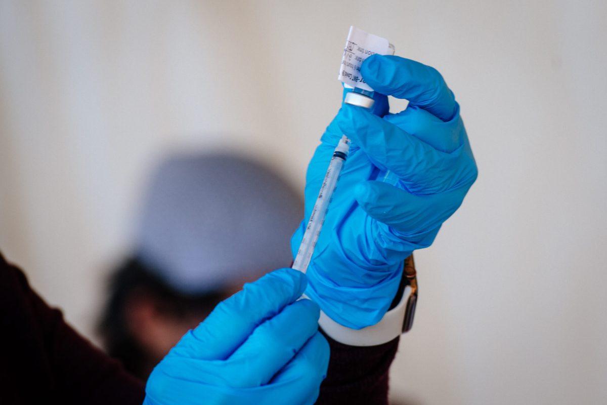 Close-up of hands wearing PPE (Personal Protective Equipment) gloves are filling a syringe from a COVID-19 vaccine vial at the UAB COVID-19 Vaccination Site at Parker High School on February 10, 2021.